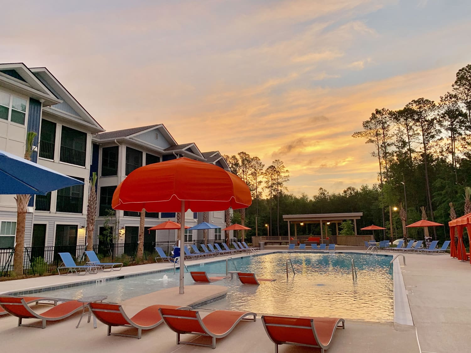 Discover the idyllic apartments in Bluffton, nestled between breathtaking landscapes, boasting a serene pool area complete with comfortable chairs and shady umbrellas.