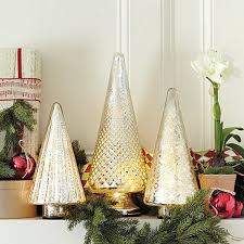 Three christmas trees on a mantle, perfect for decorating your whole apartment with festive charm.
