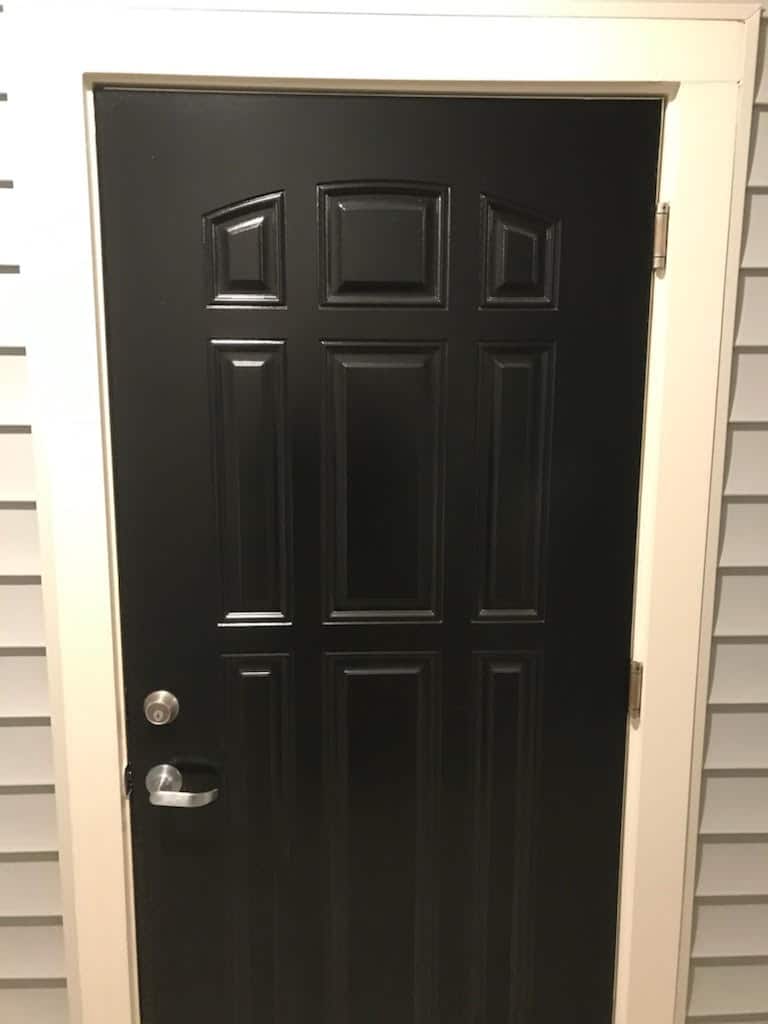 A black door in a house with white trim in an apartment complex.