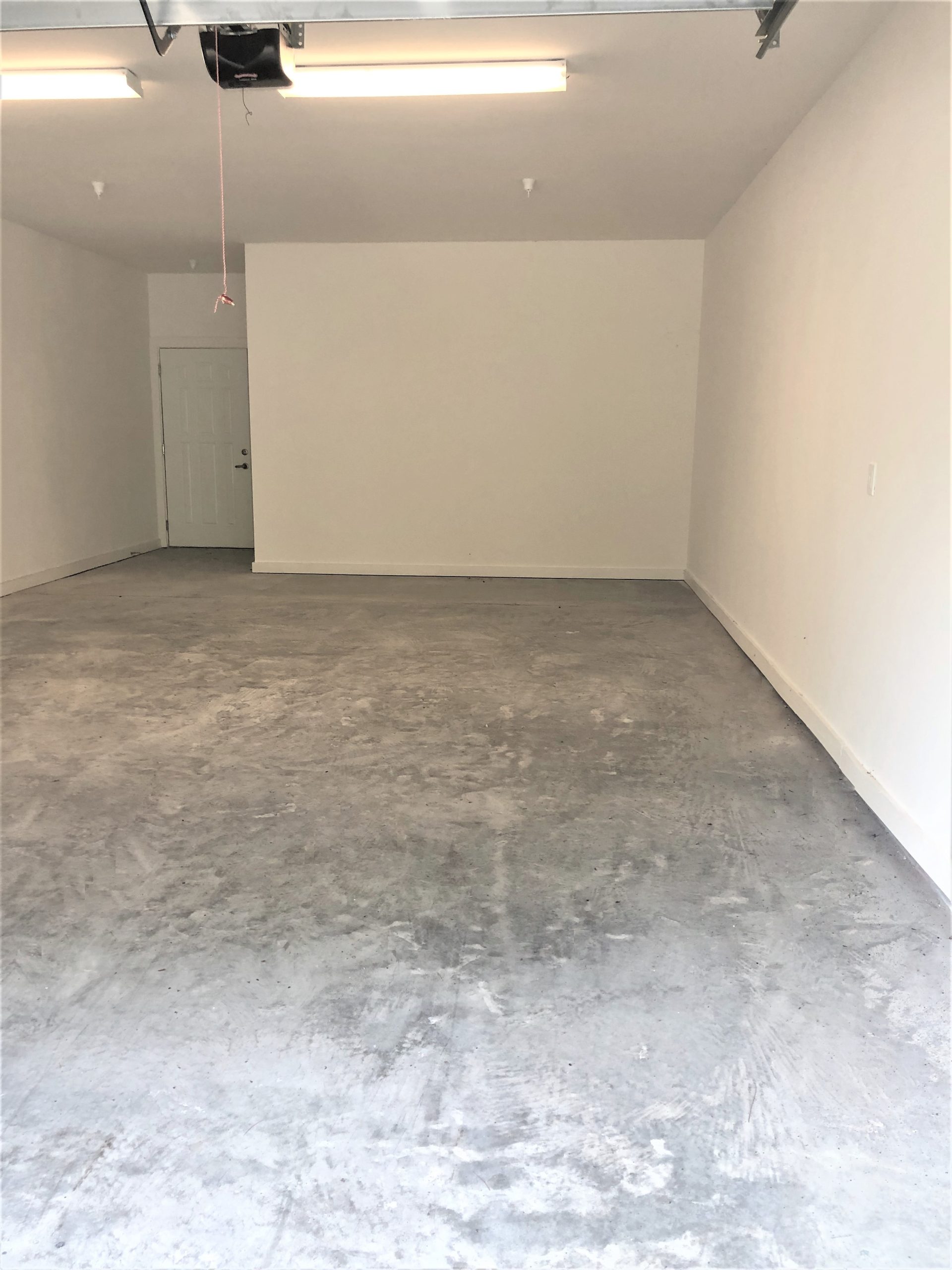 An empty garage with concrete floors and a door, suitable for apartments with garages.