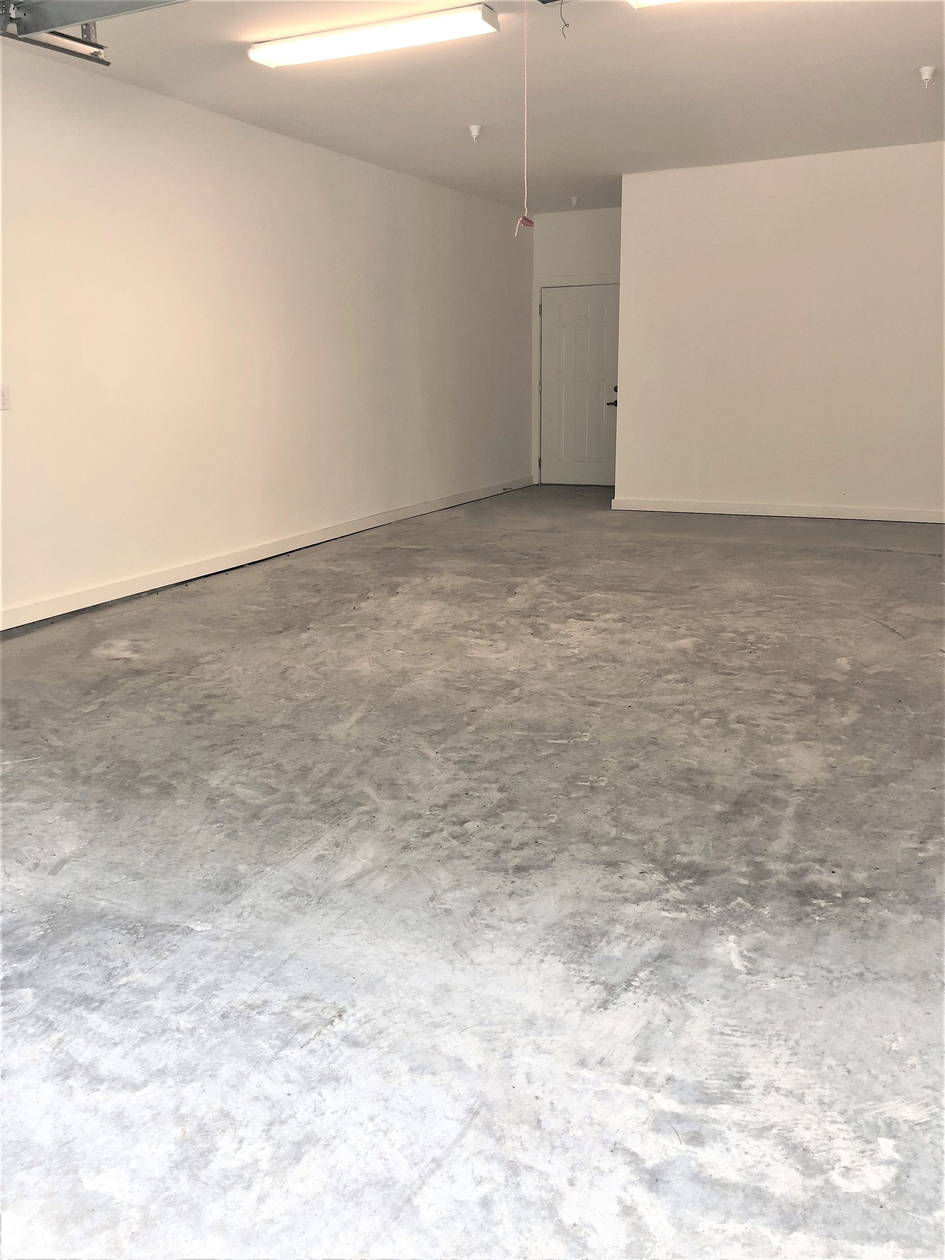 An expansive vacant room with a solid concrete floor.