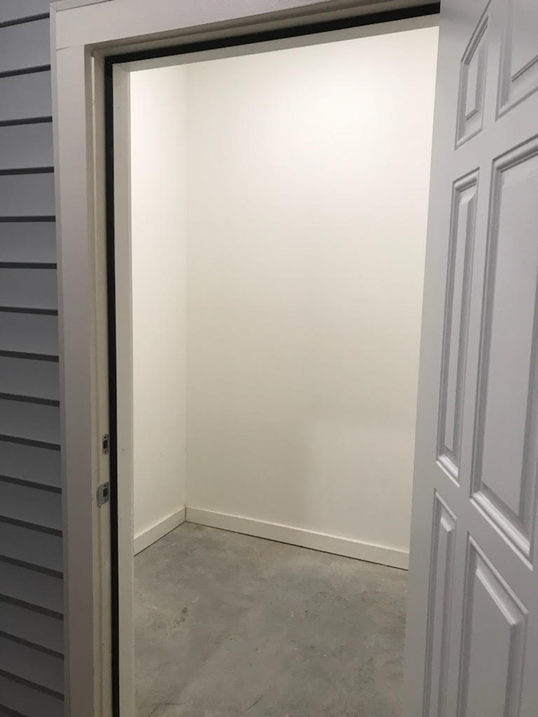 An open door to a room with a white door in an apartment complex.