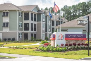 The entrance to a apartment complex with an american flag.