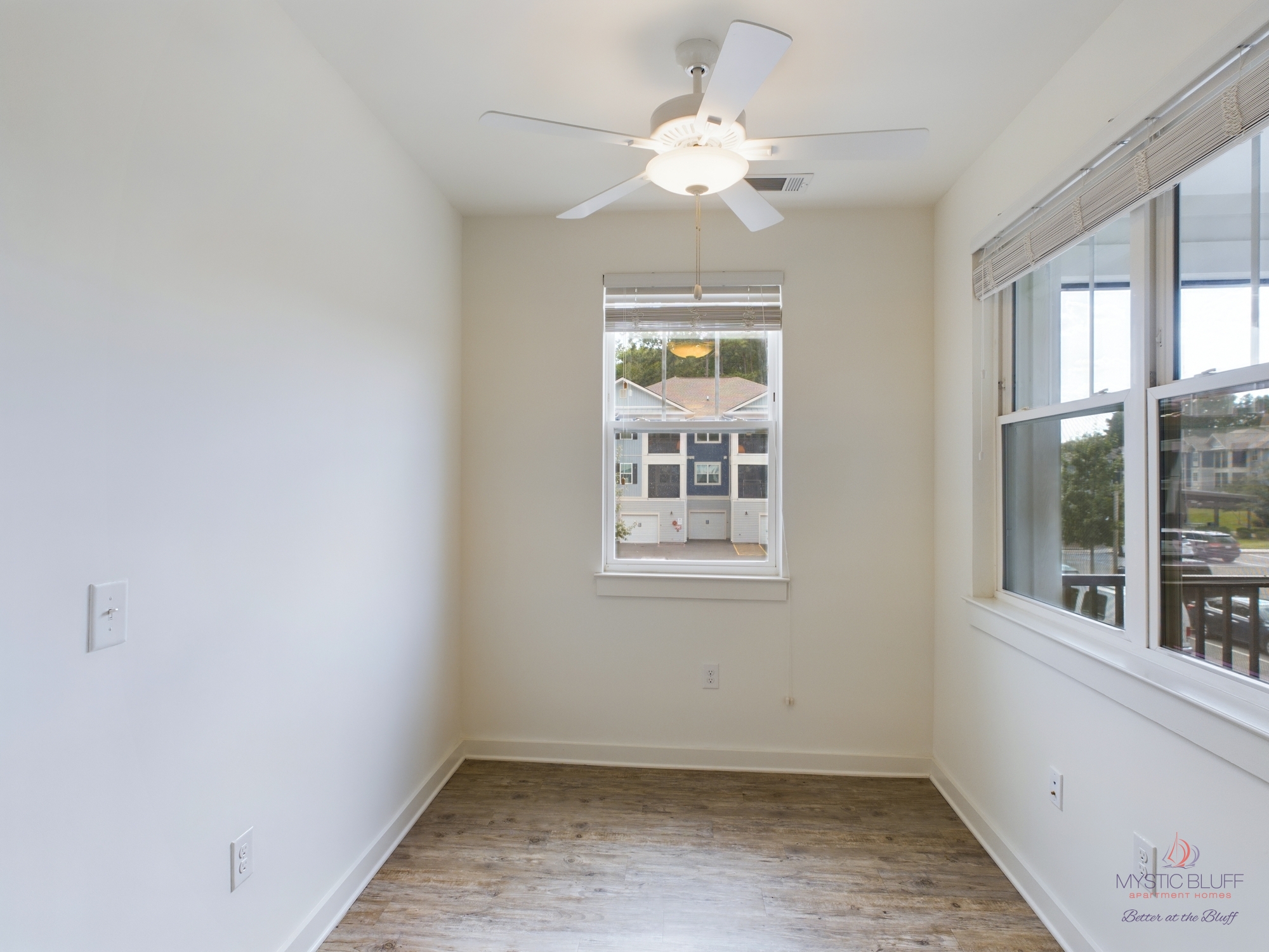 A spacious one-bedroom apartment with hardwood floors and a ceiling fan.