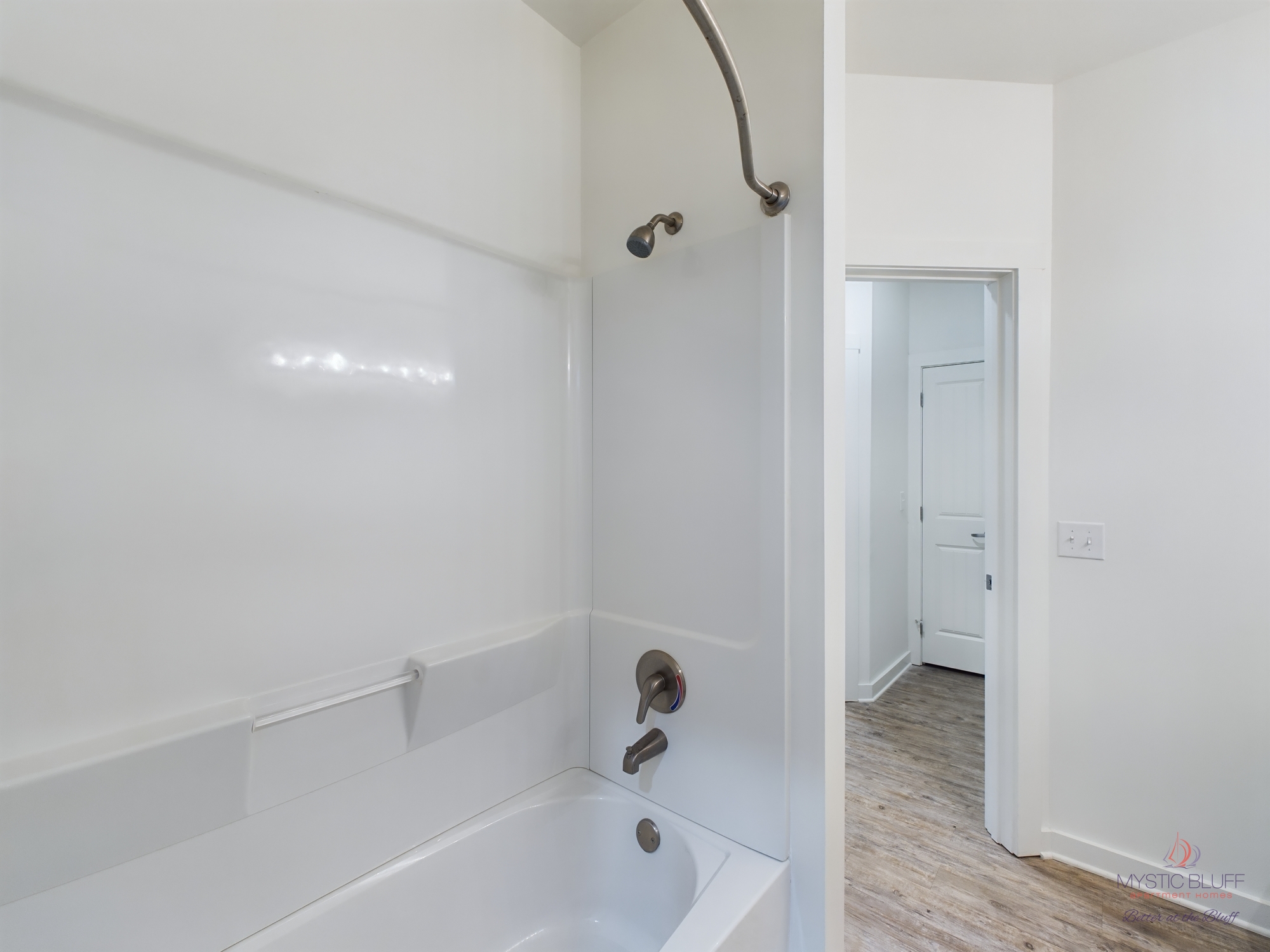 A white bathroom in an apartment with a tub and shower.