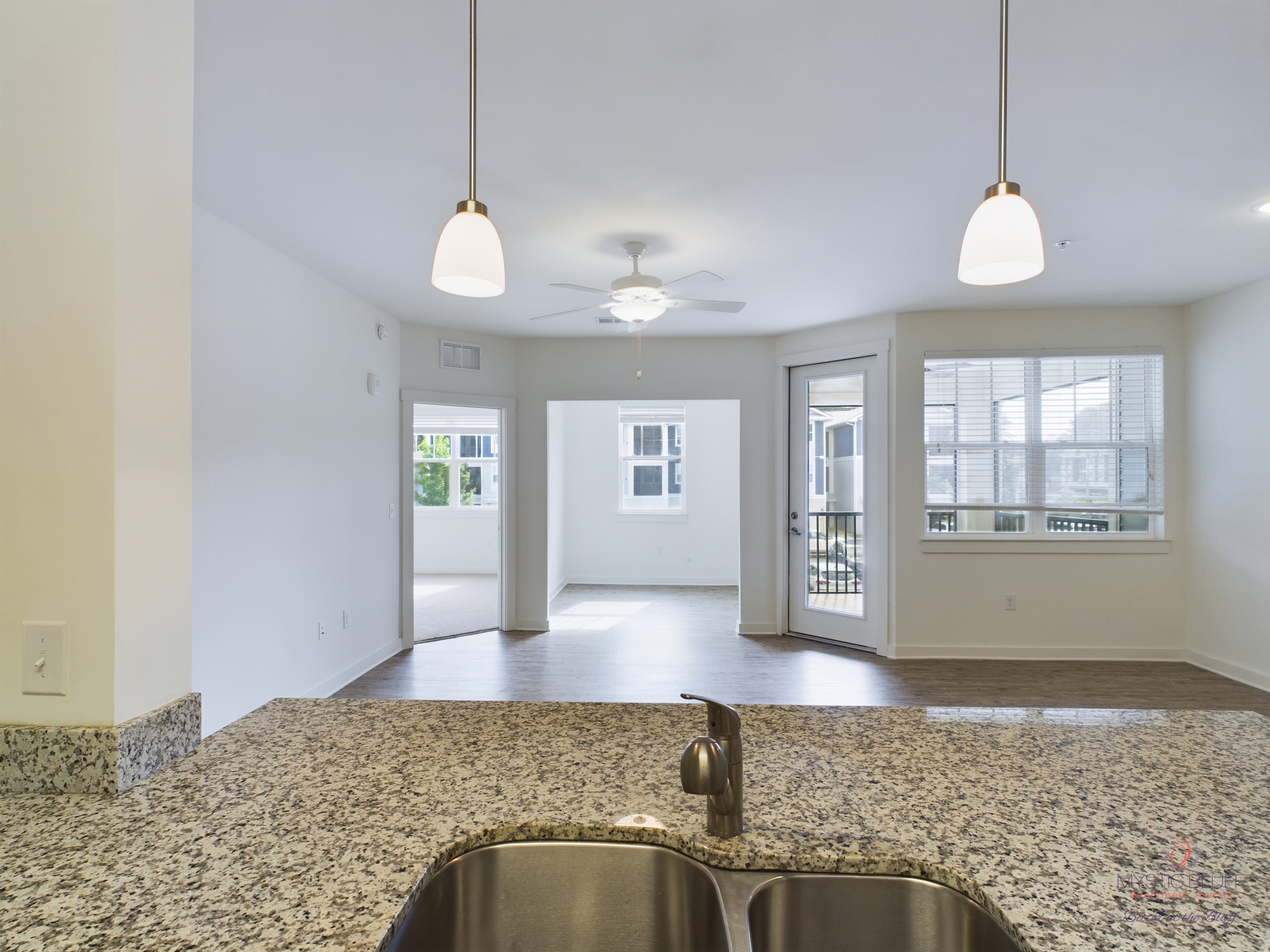 An empty kitchen with granite counter tops and a ceiling fan in one bedroom apartments.