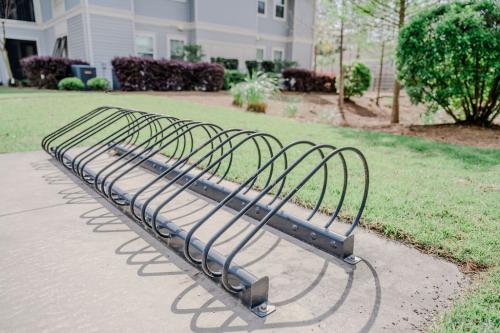 Apartments in Bluffton A black metal bike rack is installed on a concrete pad in front of a residential building with a well-maintained lawn and shrubs.