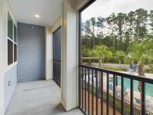 Apartments in Bluffton A covered balcony with a view of a swimming pool and trees, featuring gray railings and exterior walls.