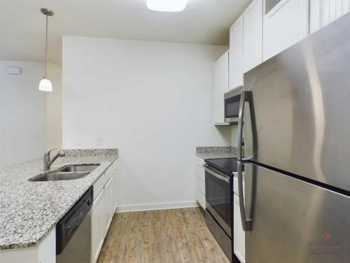 Apartments in Bluffton A modern kitchen with granite countertops, stainless steel appliances including a refrigerator, dishwasher, oven, and microwave, and wooden flooring.