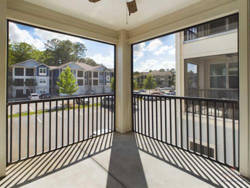 Apartments in Bluffton A screened-in balcony with a black railing overlooking an apartment complex and parking lot.