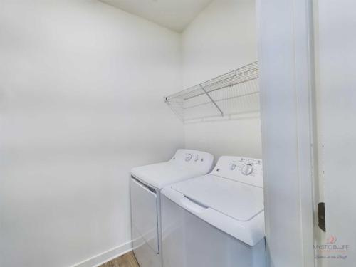 Apartments in Bluffton A small laundry room featuring a white washing machine and dryer side by side under a wire shelf against a white wall.