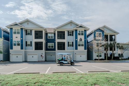 Apartments in Bluffton A three-story apartment building with blue and white exterior features a parking area in the front. A golf cart with one occupant is seen driving in the parking lot.